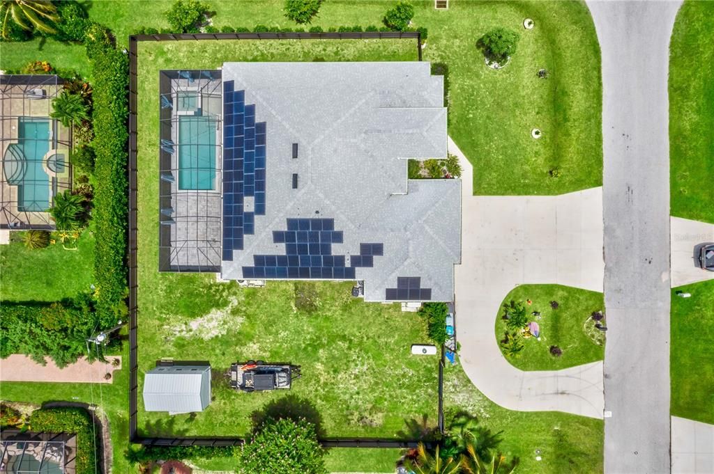 Aerial view of this home with solar panels, curved driveway and a huge TRIPLE lot!