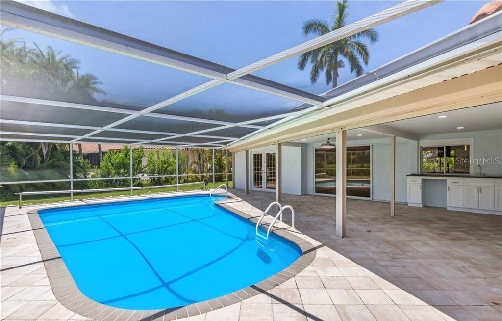 View of swimming pool with a patio, glass enclosure, and sink