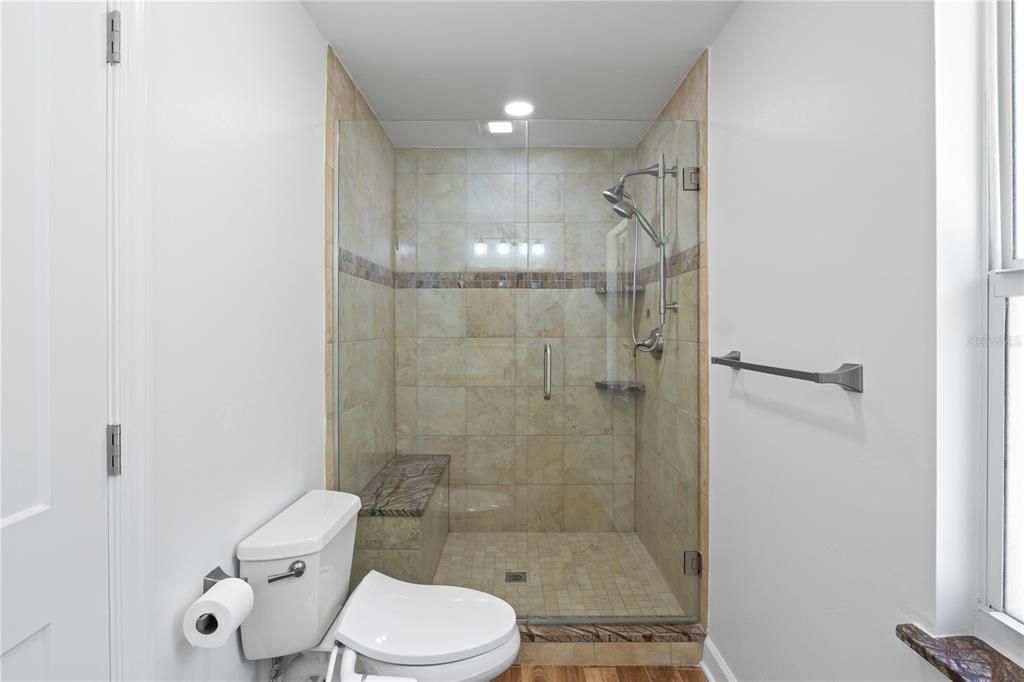 Large walk in shower with granite topped bench, multiple showerheads and accent tile!