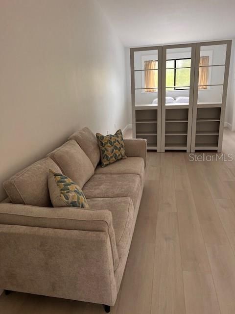 Living room space with wall unit separating bedroom area.