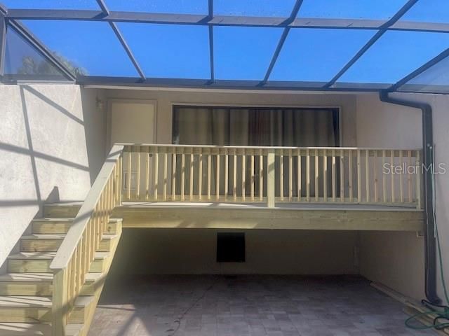 Front of unit with brand new deck and stairs. Unit is elevated within a screened in paved porch lanai, allowing for a large area below for outdoor living furniture or garden.