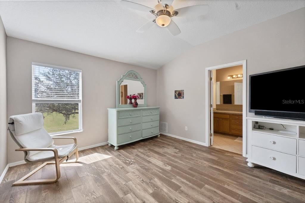 Owners suite featuring laminate flooring, a built out walk-in closet, and ensuite bathroom.