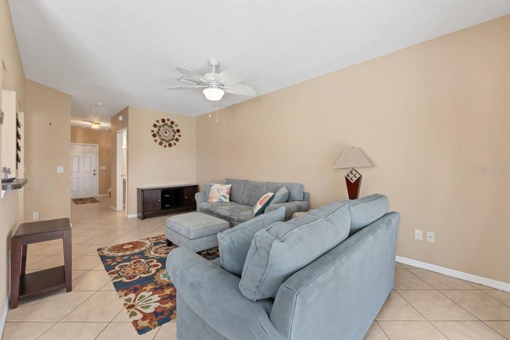 Living room featuring high ceilings, modern tile flooring, and sliding glass doors that lead to the screened-in covered lanai.