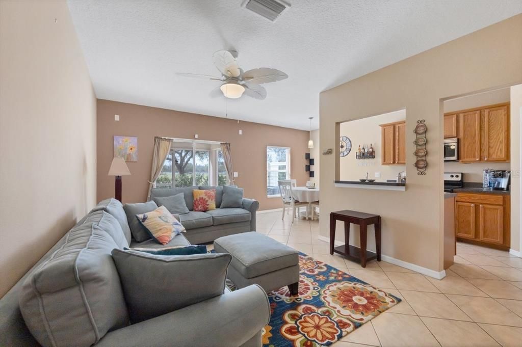 Living room featuring high ceilings, modern tile flooring, and sliding glass doors that lead to the screened-in covered lanai.