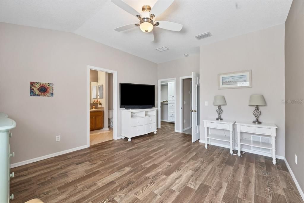 Owners suite featuring laminate flooring, a built out walk-in closet, and ensuite bathroom.