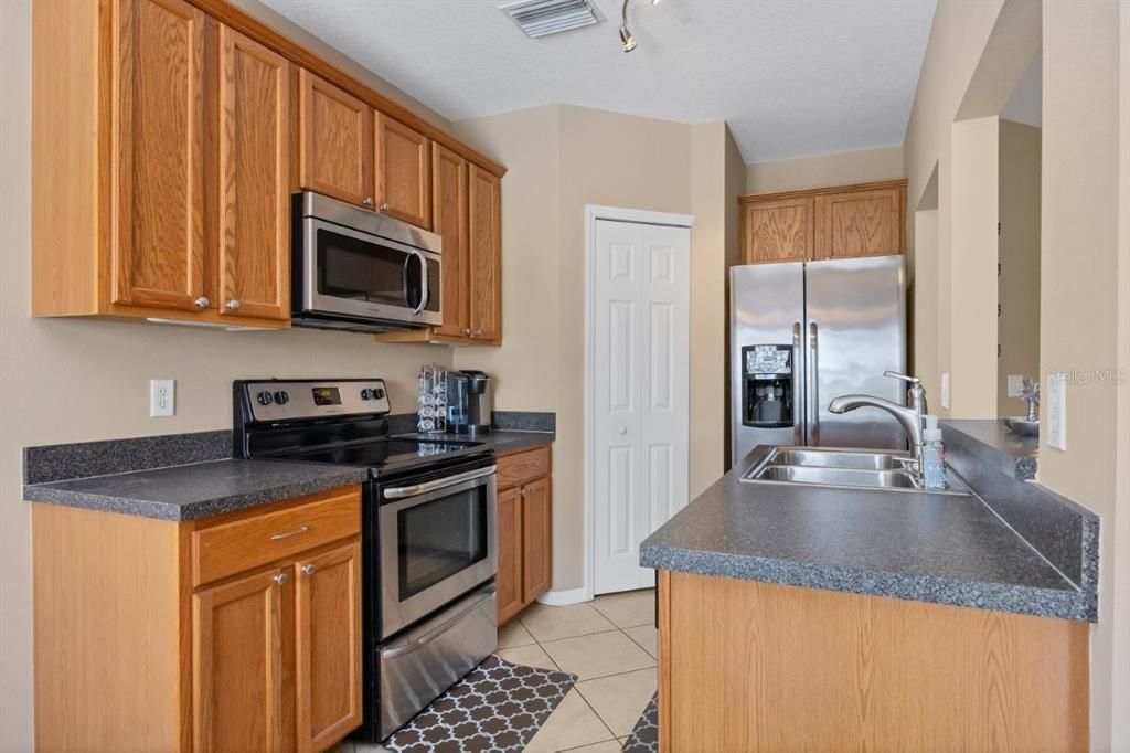 Galley style kitchen featuring wood cabinets, stainless steel appliances, and a large pantry.