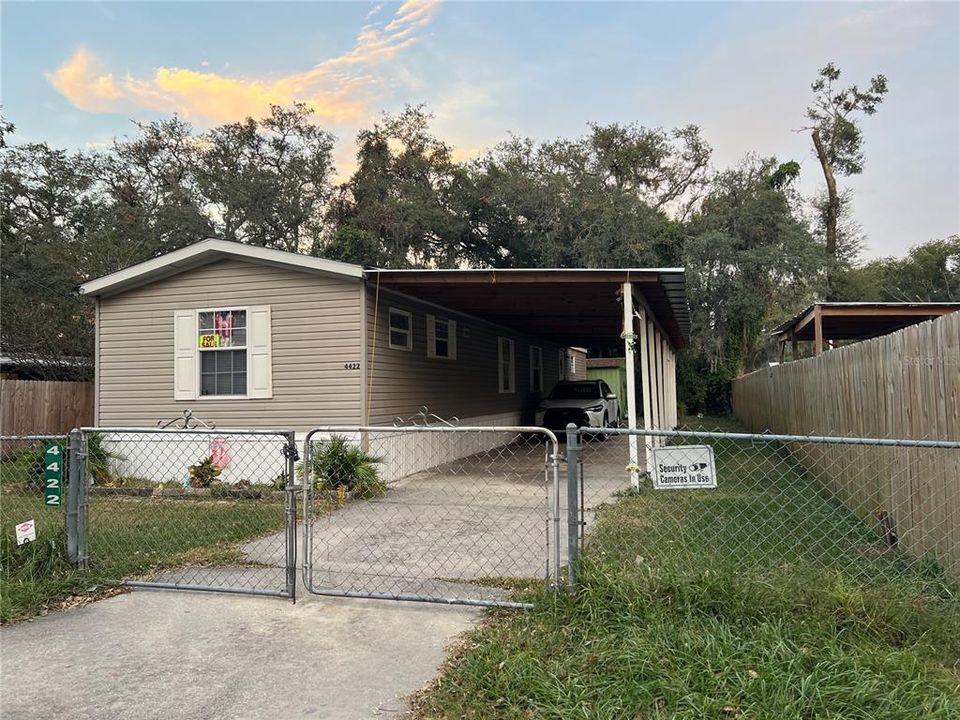 Fenced front view with carport area.