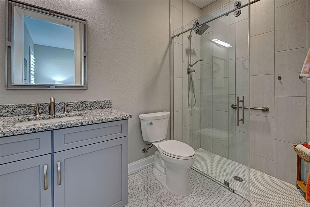 Granite countertops, a frameless glass enclosure and nickel rain head with compliant grab bar complete this elegant 2nd full bathroom.