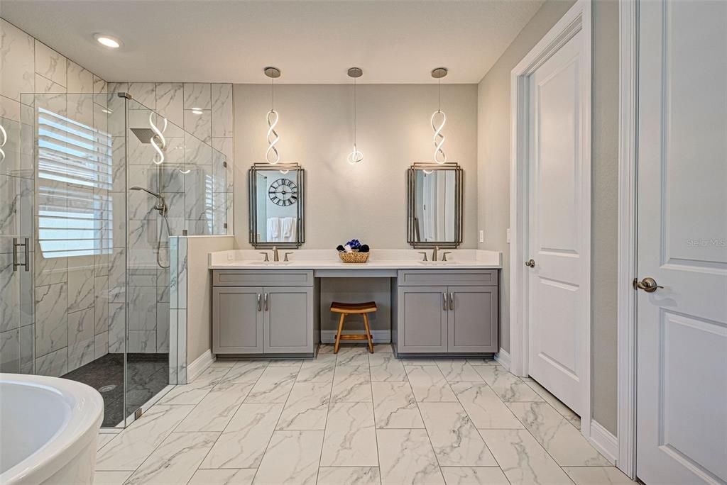 Custom designed, spa-like primary bathroom with a frameless glass shower, a gorgeous, free-standing tub and dual quartz vanities.