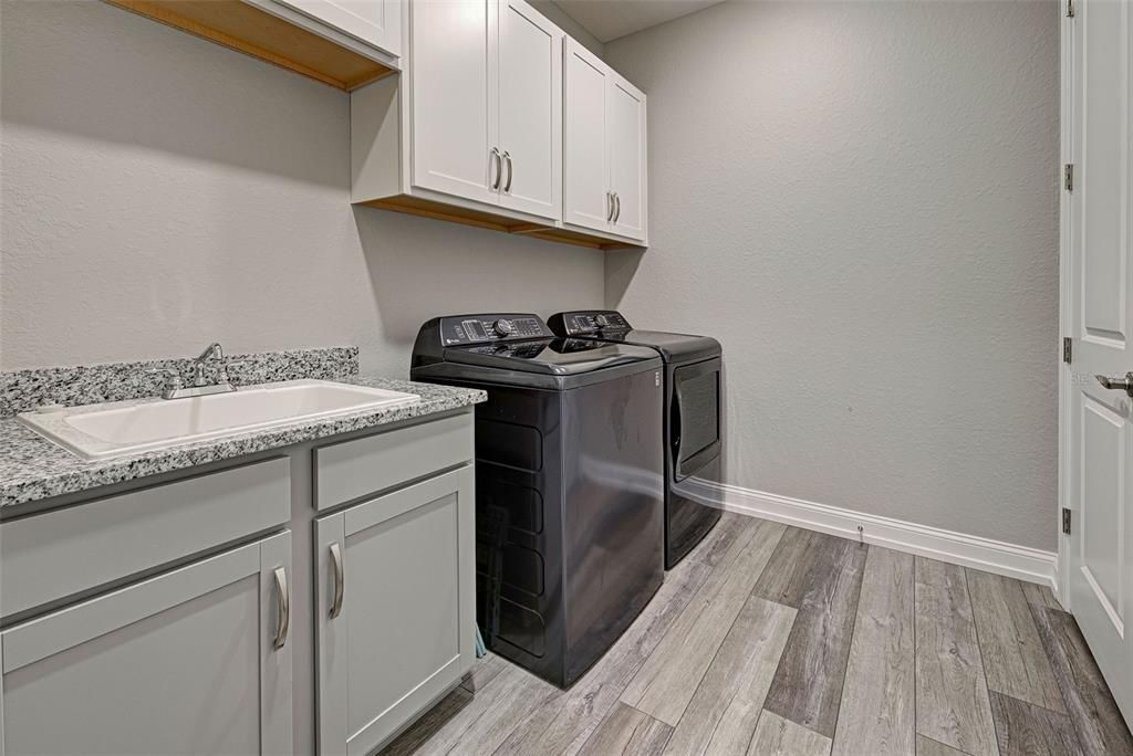 Interior laundry room has granite counters, sink and so much storage space.