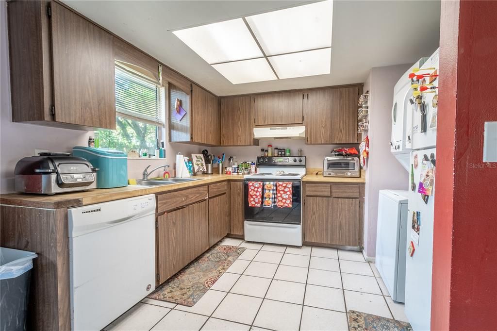 (Unit B) The kitchen has solid countertops, a range with an exhaust fan, a dual stainless steel sink beneath a window for natural light, a ceramic tile floor, plenty of cabinet space, a dishwasher and a refrigerator.  The kitchen has a hookup for a stackable washer and dryer.