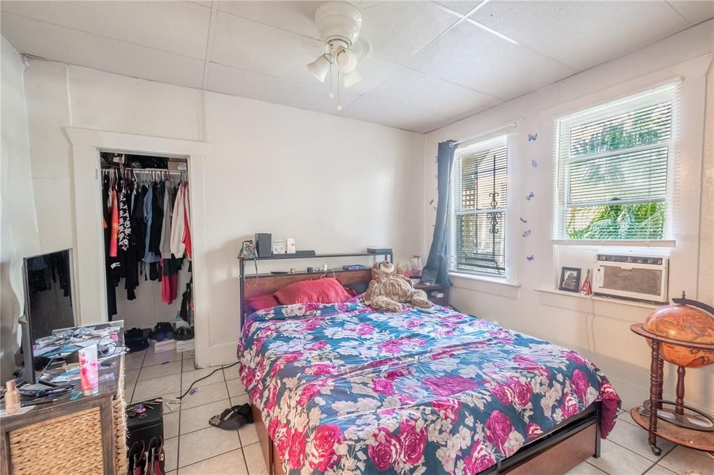 Primary bedroom (Unit A) has a ceiling fan with light kit, window A/C, built-in closet and ceramic tile floor.