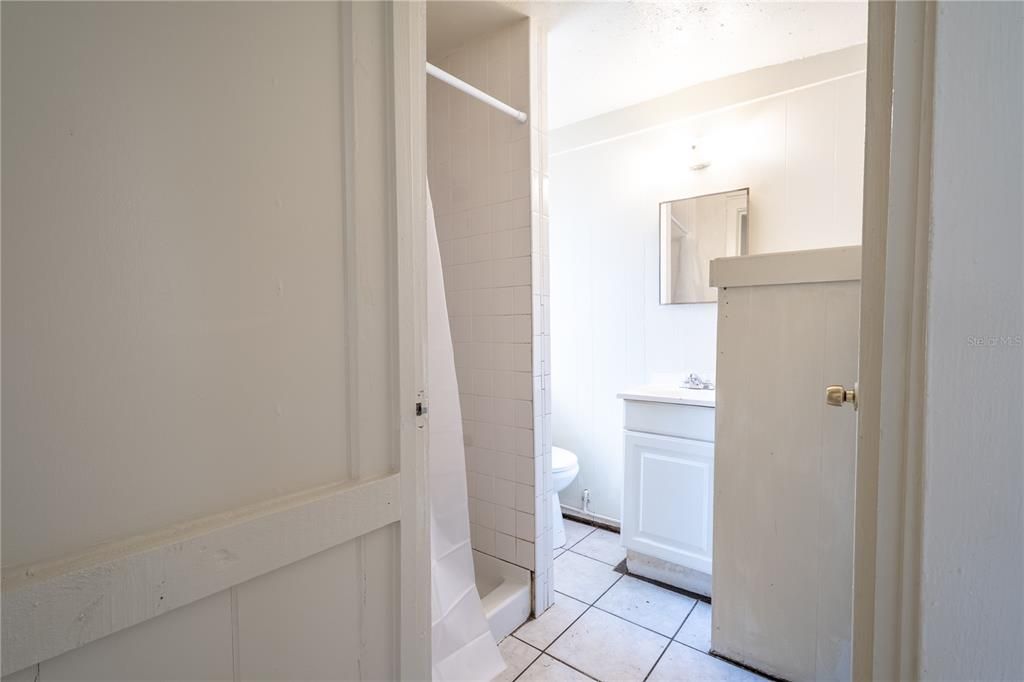 (Unit A) Bathroom has a ceramic tile floor, a step in shower and a mirrored vanity with storage.