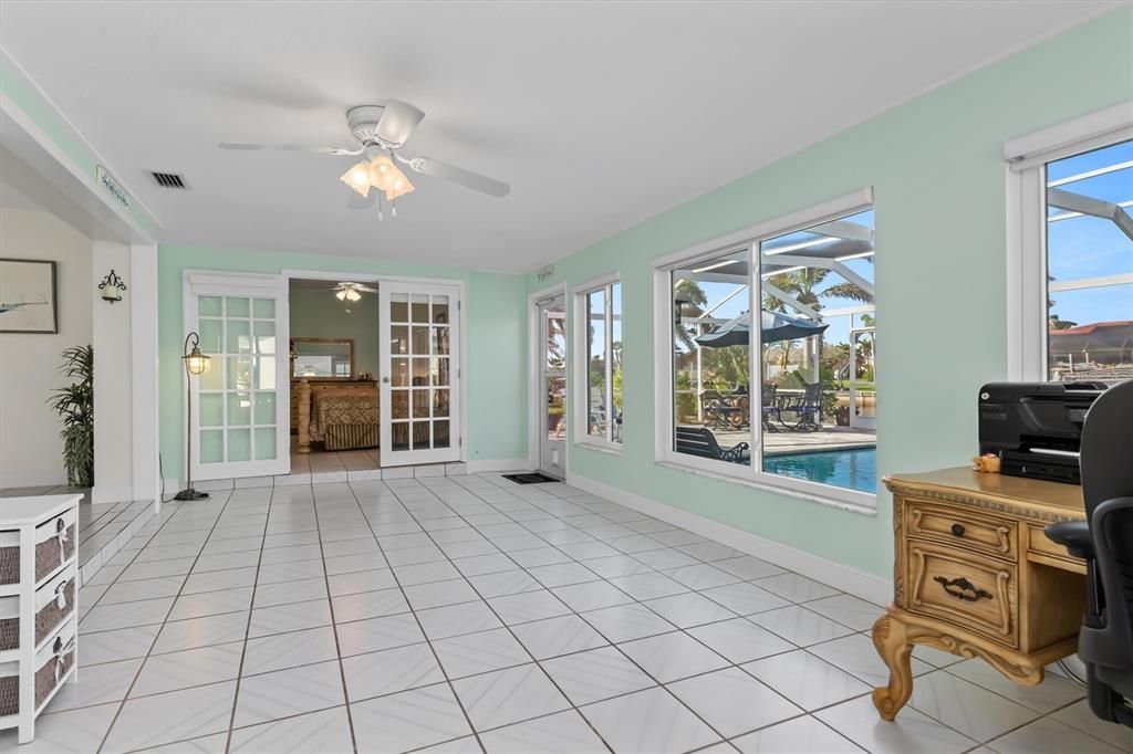 Florida Room view towards Guest Suite accessible via the French Doors. Enjoy convenient access to your expansive screened pool area, complete with new pavers.