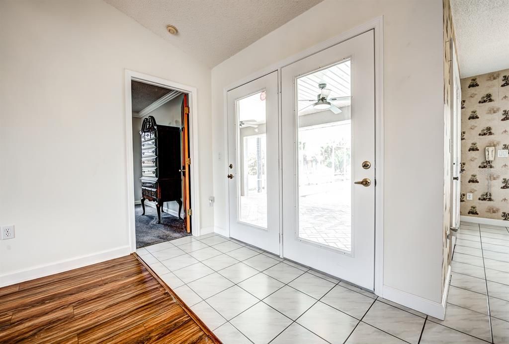 French doors lead to the covered lanai from the dining area in the great room. The door on the left leads you to the primary bedroom suite.