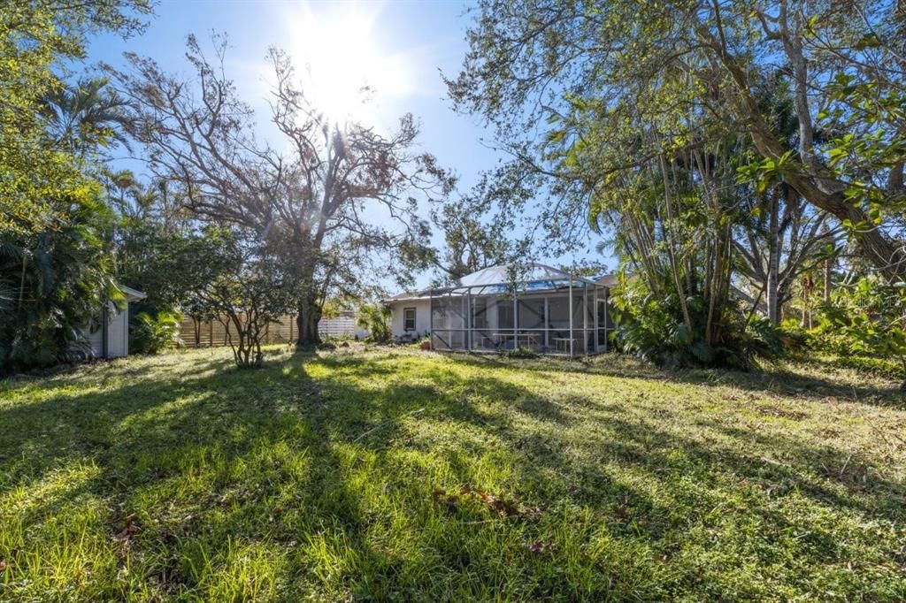 Rear elevation of the home showing the large screened-in lanai and mature trees.