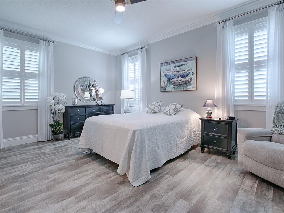 PRIMARY BEDROOM WITH PLANTATION SHUTTERS AND CUSTOM FAN.