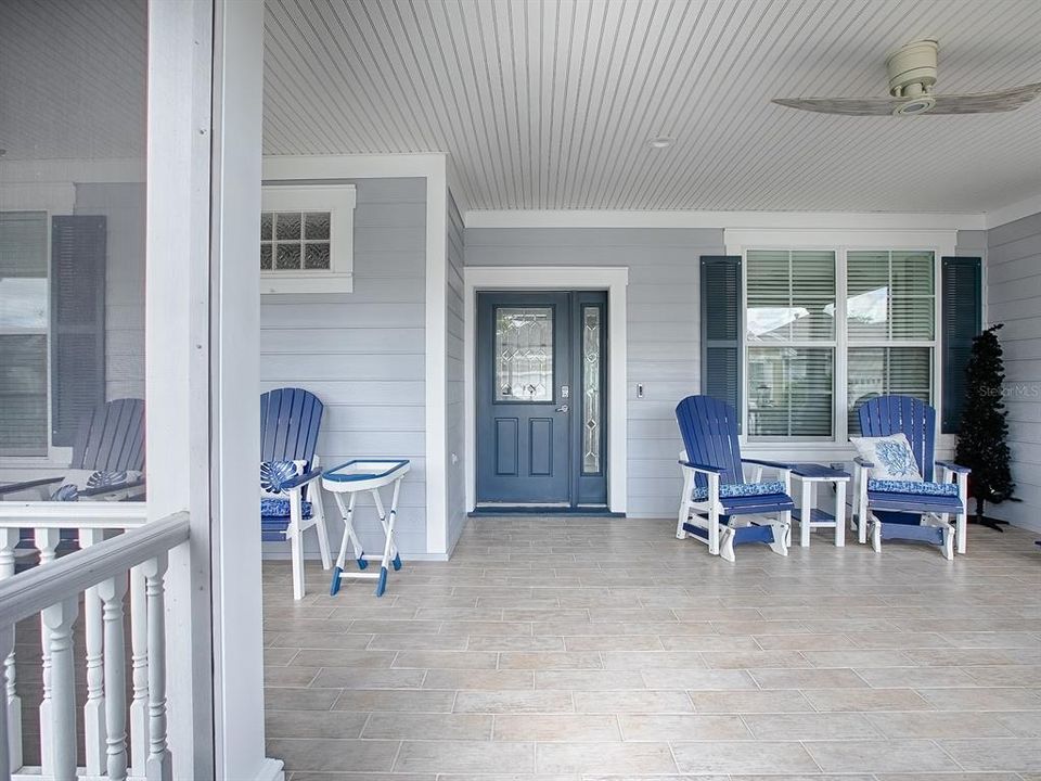 SCREENED IN FRONT PORCH WITH WOOD LOOK PORCELAIN TILE FLOORING. DECORATIVE SHUTTERS, BEADBOARD CEILING, AND CUSTOM CEILING FANS.