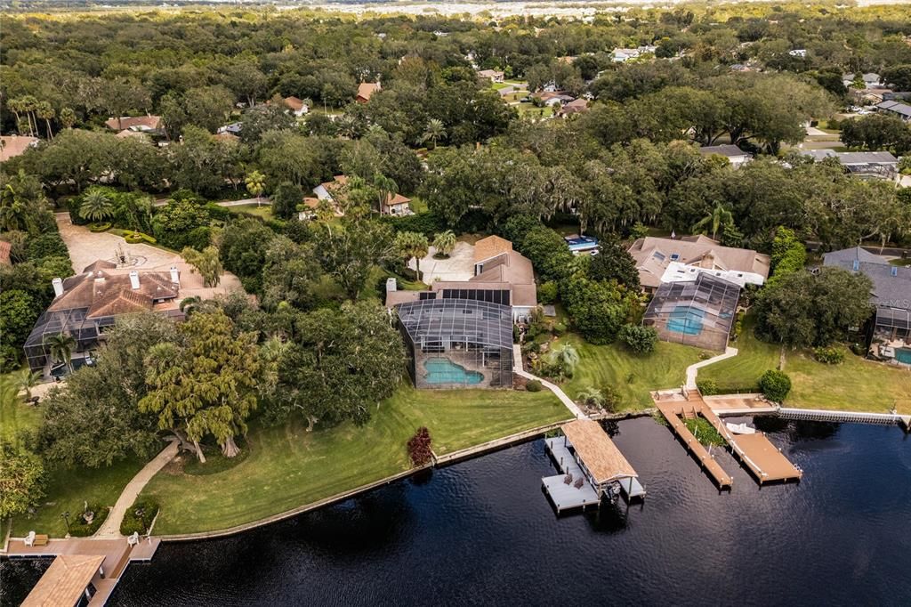 Aerial view of the back of the property featuring the pool, backyard and boat house.