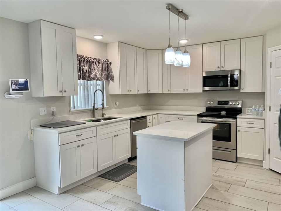 Modern open kitchen space with stainless steel appliances, beautiful ceramic tile flooring throughout the main living areas, a large closet pantry and 42" cabinets for lots of storage.