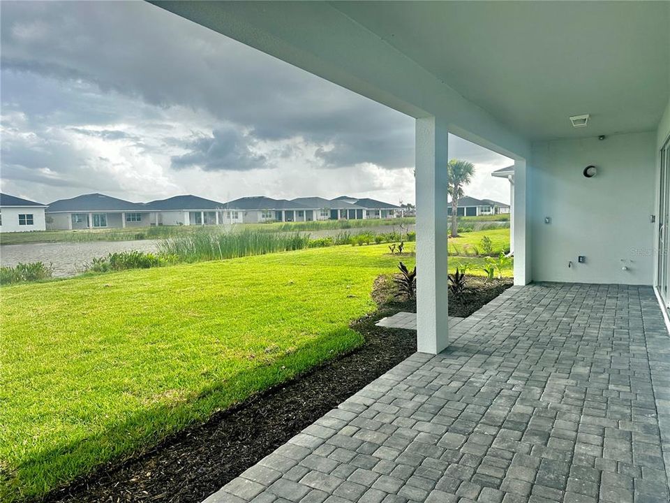 Covered lanai with exterior full height privacy wall, pre-plumbing for future outdoor kitchen, and water view of pond