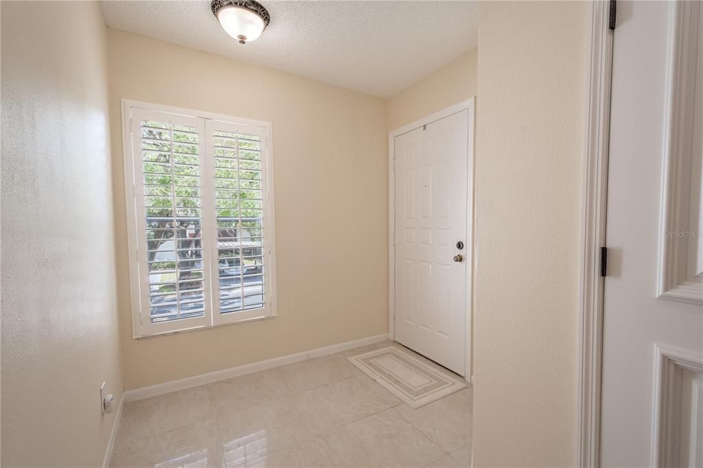 Spacious foyer, with ceramic tile flooring, overhead lighting, a large window with plantation shutter for plenty of natural light.