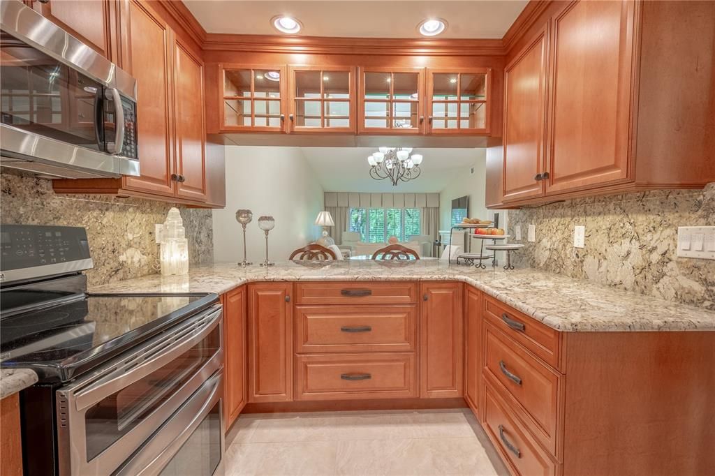 The kitchen is open to the dining and living room, framed by glass door cabinets.