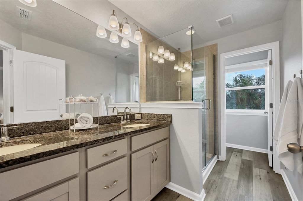 Primary Bathroom with Seamless shower door, granite top dual vanity & private water closet