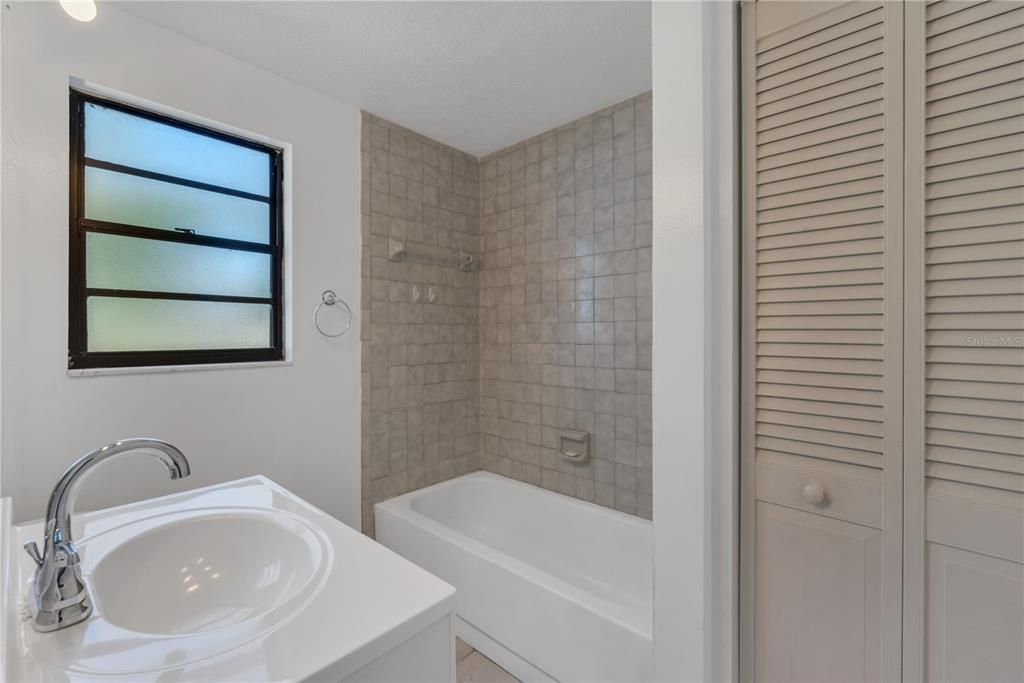 The guest bathroom has a newer vanity and tub/shower combination.