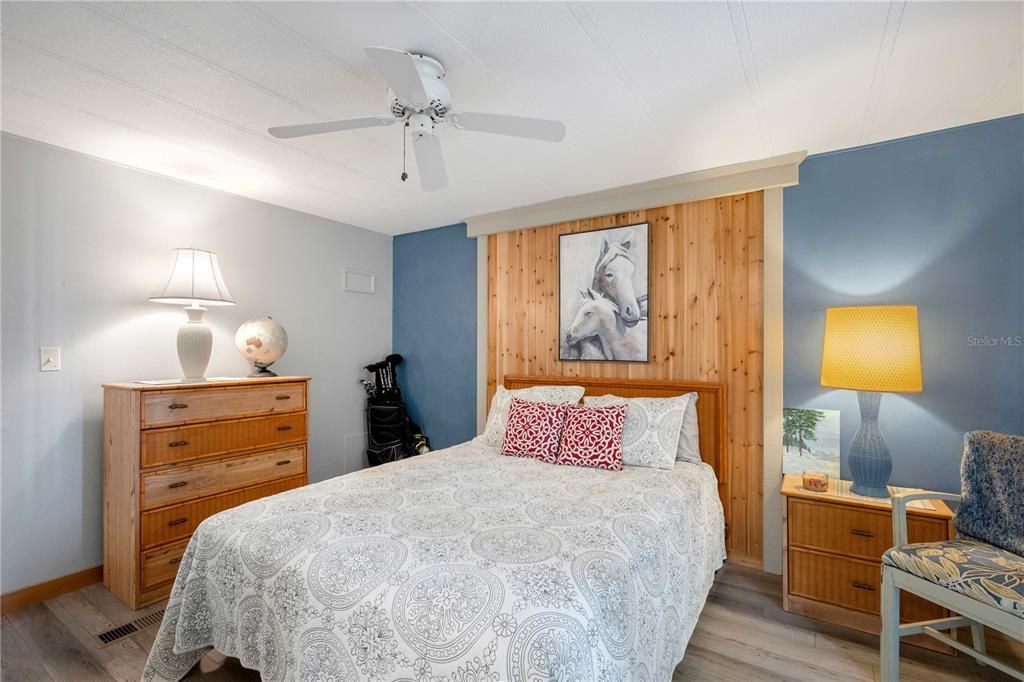 Primary bedroom with wood accent wall and custom closet doors