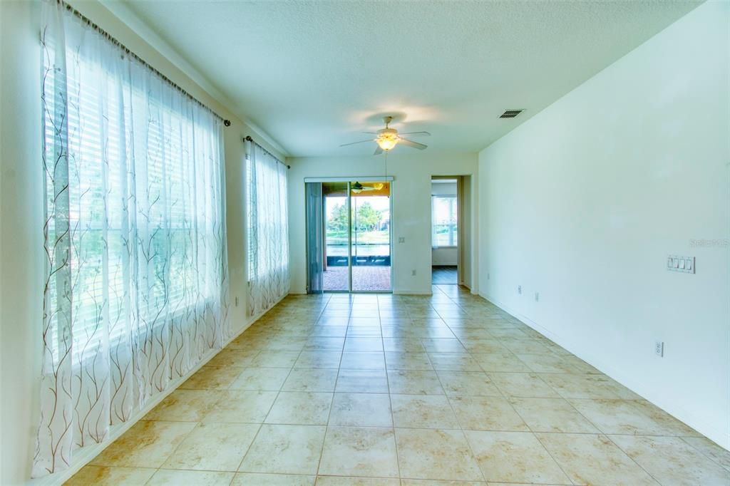 The floor tile are oversize, there are horizontal blinds on the windows and verticals on the sliders, ceiling fans above