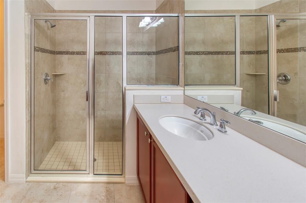 In the primary bath, find UPGRADED counters, UNDER-MOUNT sinks, upgraded shower tile, with GLASS insert listello