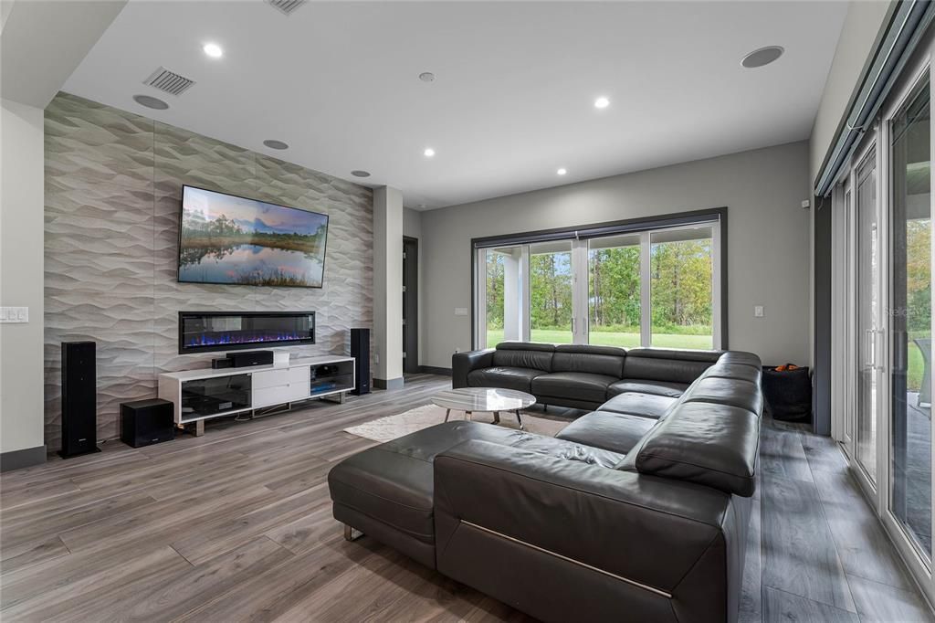 Great Room:Bright and airy, this great room features 10’ ceilings, custom lighting, and an accent wall with a 5' linear gas fireplace. The 8' sliding glass doors invite the outdoors in, creating seamless indoor-outdoor living