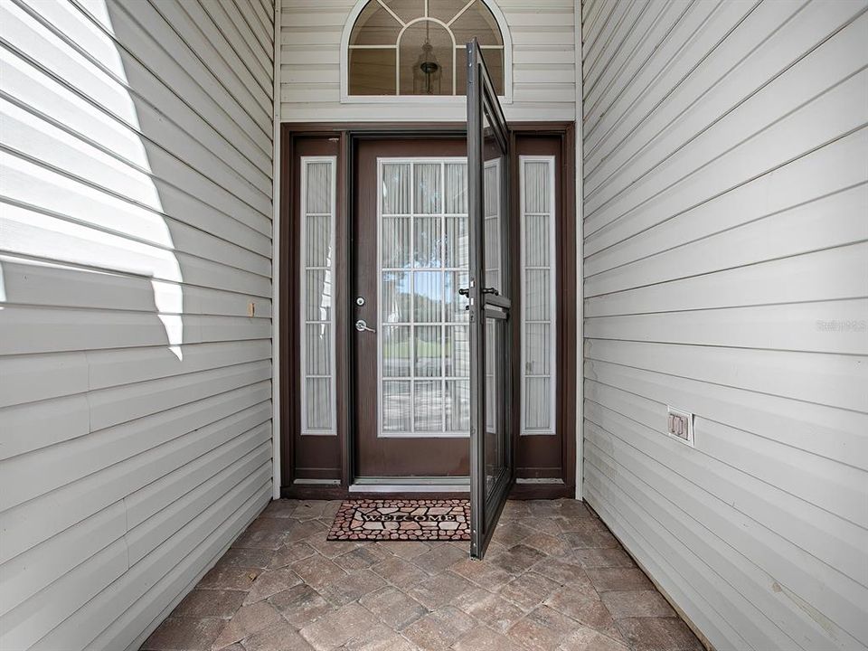 WALKWAY LEADS UP TO A BEAUTIFUL GLASS-PANED ENTRANCE DOOR WITH OVERHEAD ACCENT WINDOW