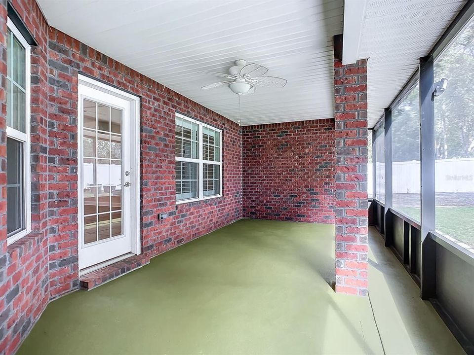 View of covered lanai with ceiling fan overlooking huge backyard