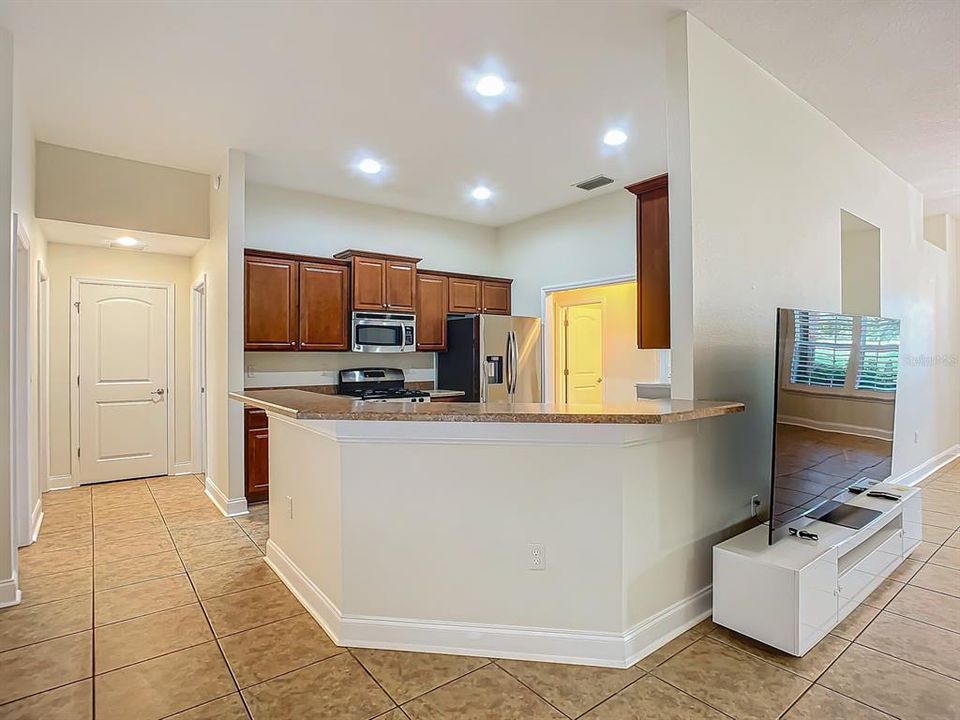 View of kitchen with bar seating and stainless steel appliances