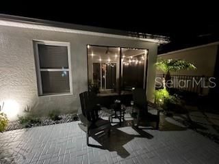 Back patio and lit screened lanai nightime  view