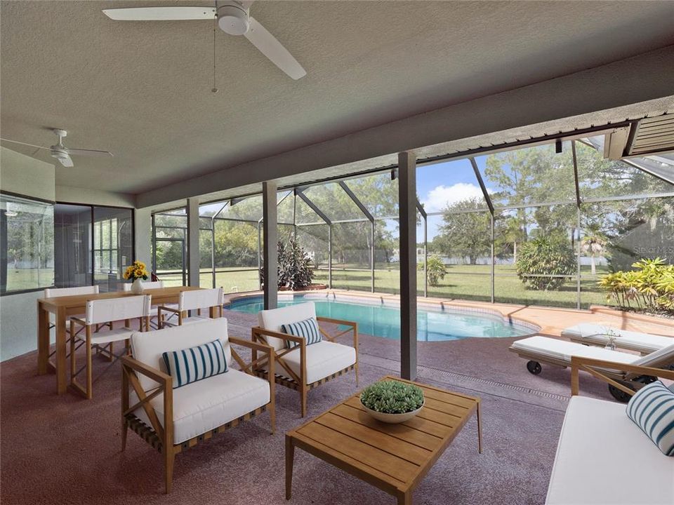 The expansive COVERED LANAI is open to the living room ideal for indoor/outdoor living and perfect for entertaining as it overlooks the SCREENED POOL, large yard and Sandhill Crane Lake beyond! Virtually Staged.