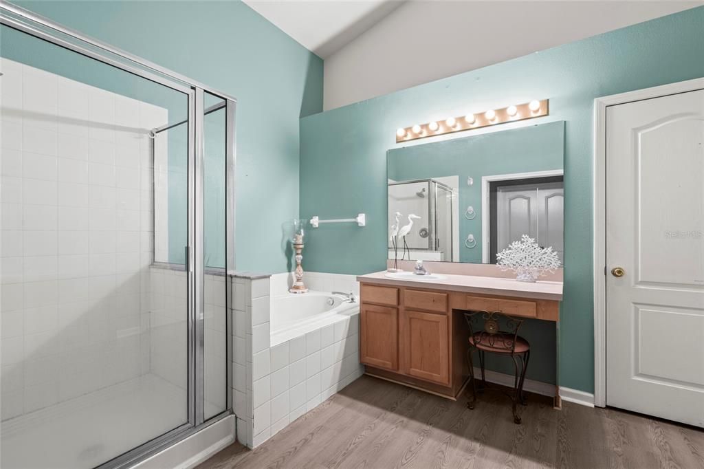 Master Bathroom with vaulted ceilings, dual sinks, garden tub, shower, water closet, and linen closet