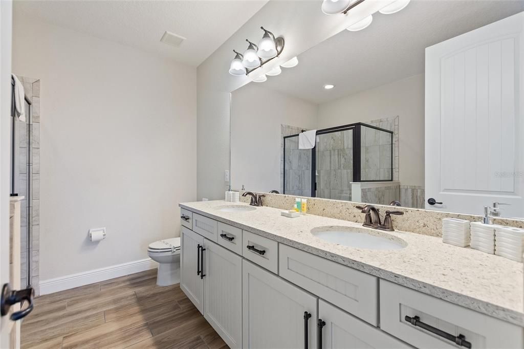 Another bathroom having a double sink vanity, garden tub, and separate shower stall.