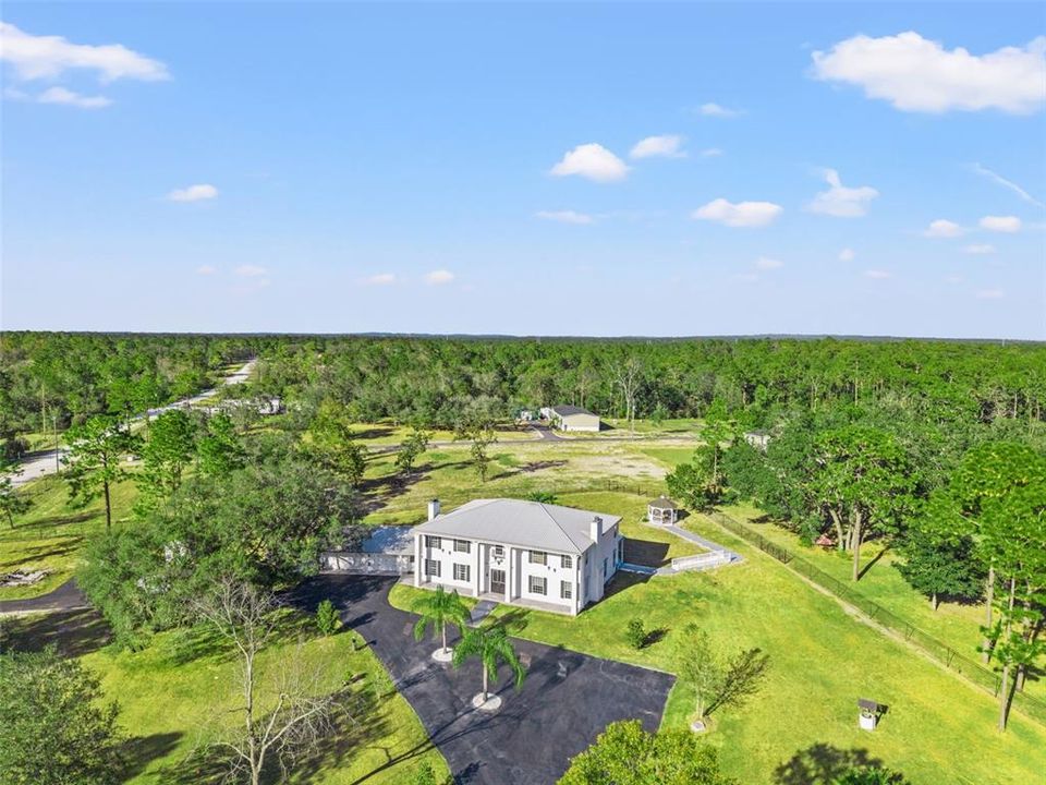 Aerial view of this Colonial-inspired estate, designed with the grandeur reminiscent of the iconic “White House.” Set on a private 2.40-acre property