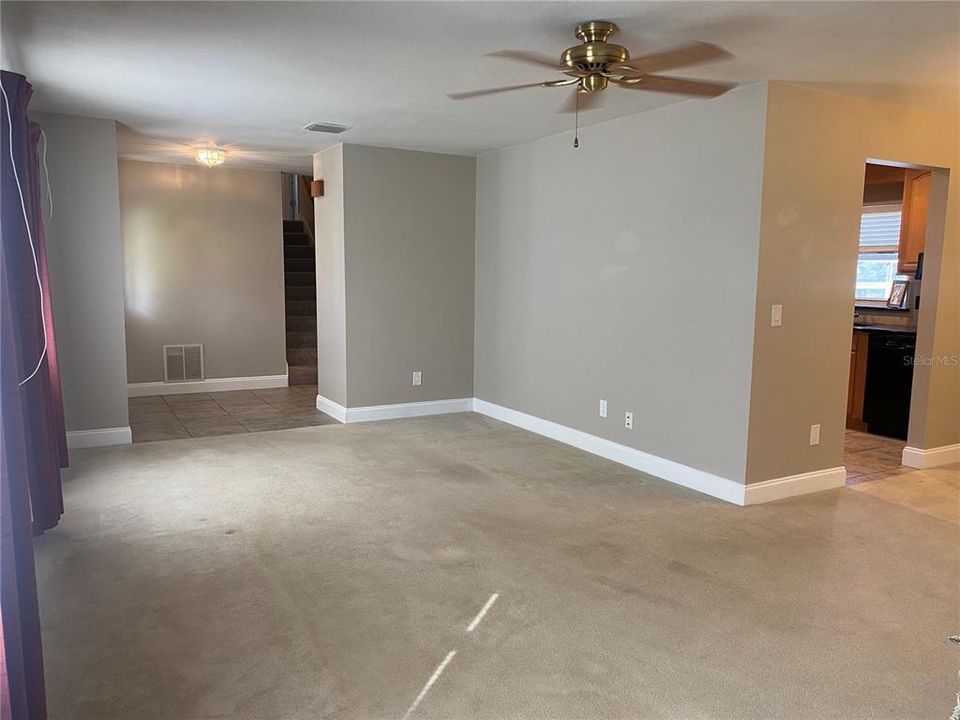 Living Room which shows where the stairs going upstairs are located, dining room to the left and (one of two entrances) leading into the kitchen.