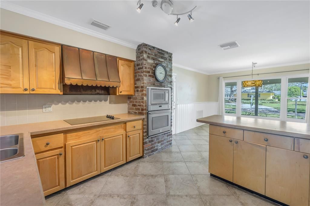 Kitchen showcases  an exposed brick wall with built in oven/microwave.