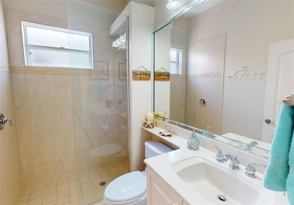 Guest bath showing walk in shower, vanity and commode.