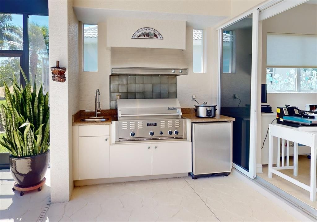 Outdoor kitchen with refrigerator and sink.