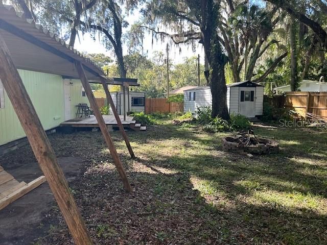 Viewing the back yard, from beside the carport, looking toward the back porch and both sheds.