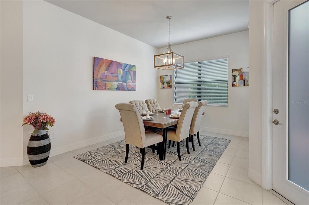 Kitchen featuring a kitchen bar, stainless steel appliances, pendant lighting, white cabinets, and an island with sink