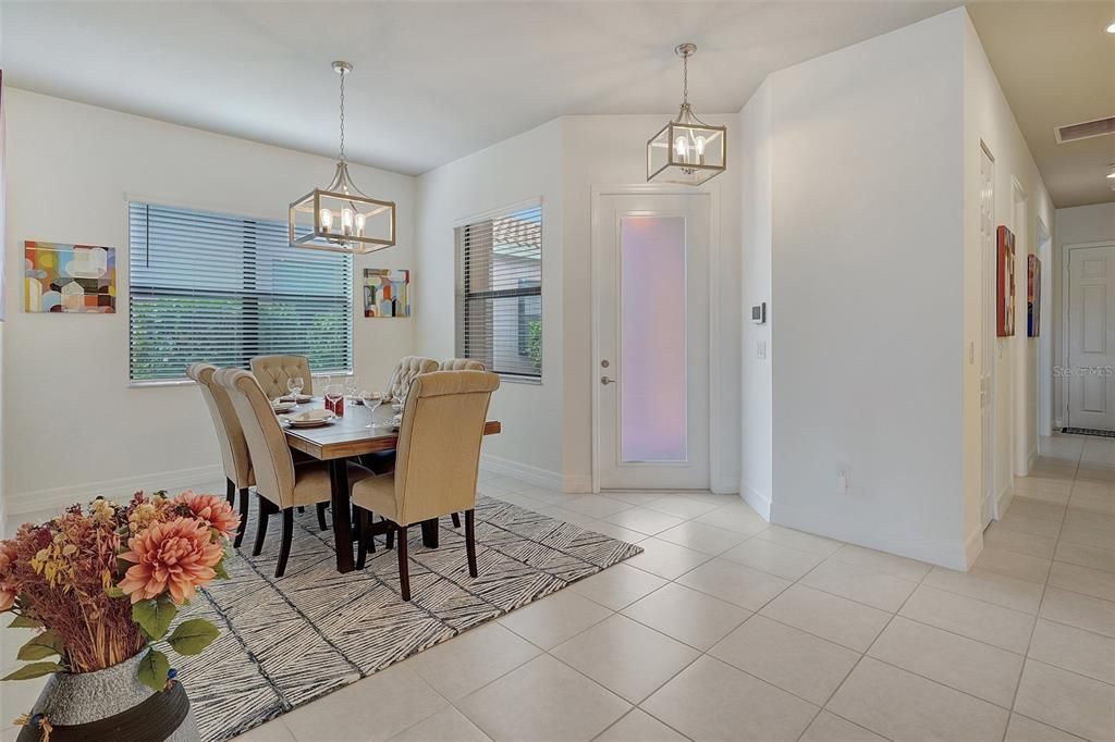 Kitchen with stainless steel appliances, decorative light fixtures, a breakfast bar area, a kitchen island with sink, and white cabinets