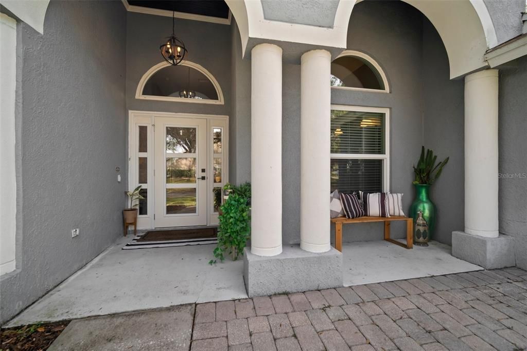 Inviting front porch with pavers and wood ceiling