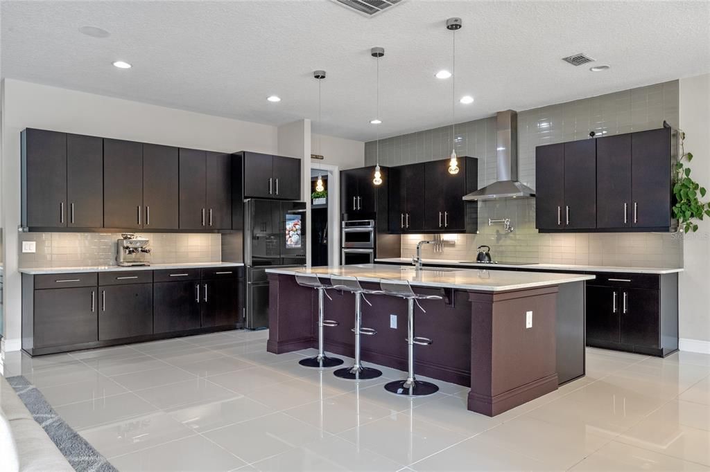 The kitchen features a large center island with eat in space, upgraded kitchenaid stainless steel appliances, 48" cabinets and quartz countertops.